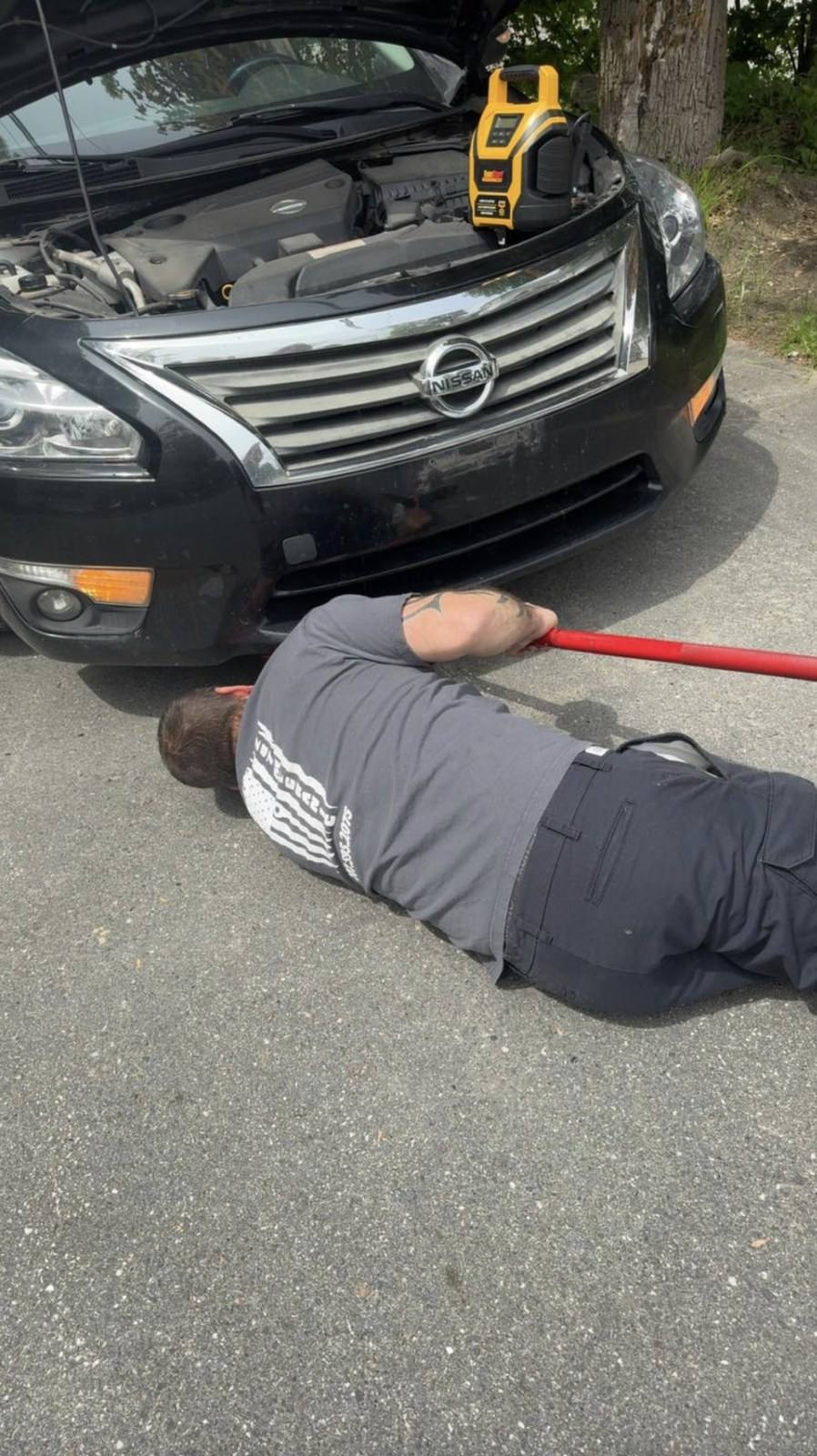 Erie mechanic working under a customer car at the curb